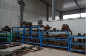 Rows of stamping dies on industrial shelving and pallets awaiting setup in a metal stamping plant